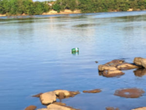 Imagem de um rio poluído com lixo nas margens